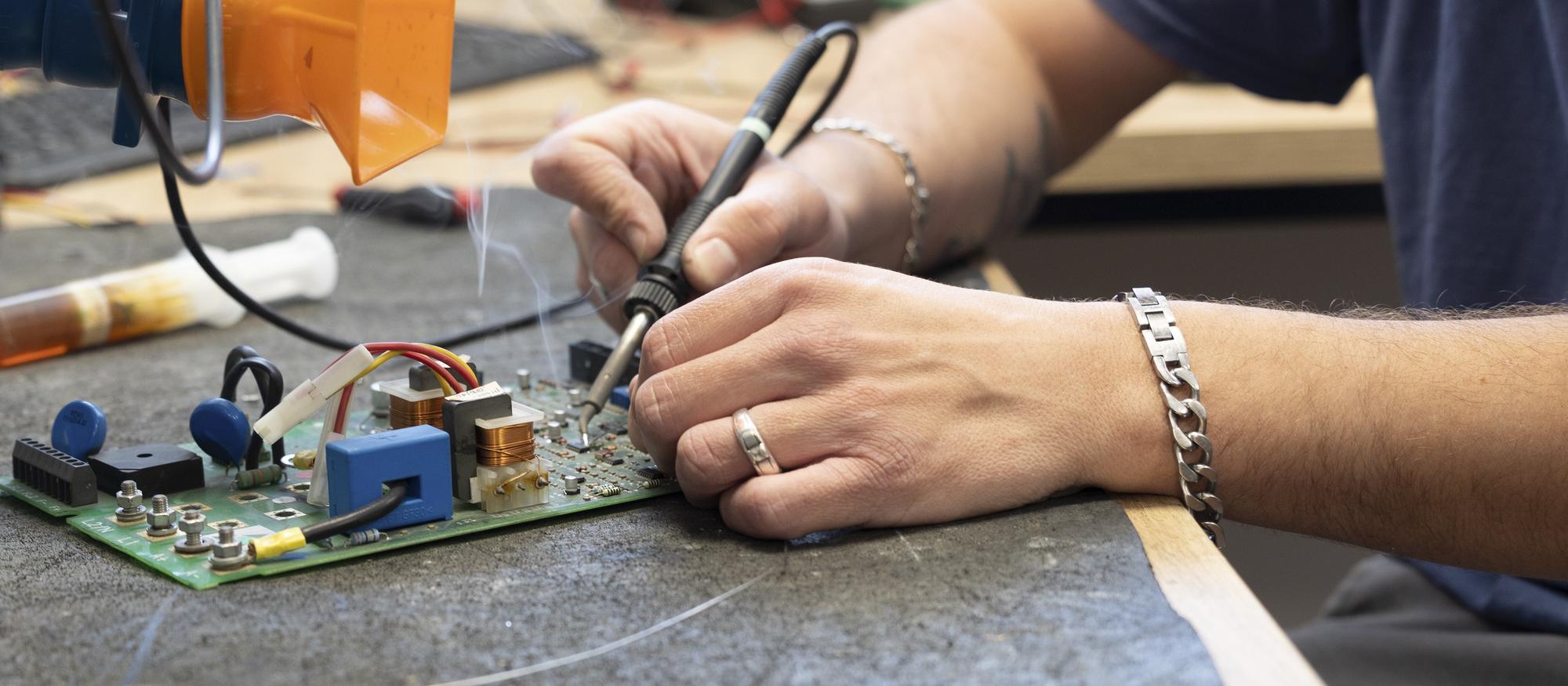 Technicien SEIA Electronique en cours de soudure sur une carte électronique industrielle